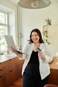 Plus size woman happily engaging with her laptop and mobile device at home.